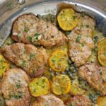 Pork piccata in a silver skillet.