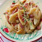 Potatoes Boulangère on a cream, red and green plate.