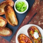 Bacon Cheddar Stuffed Potato skins on slate on a red wooden table.