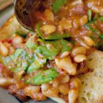 Tuscan Bean Soup being poured out of a ladle onto ciabatta bread