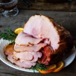 Baked Ham with Madeira and Orange on platter with slices cut.