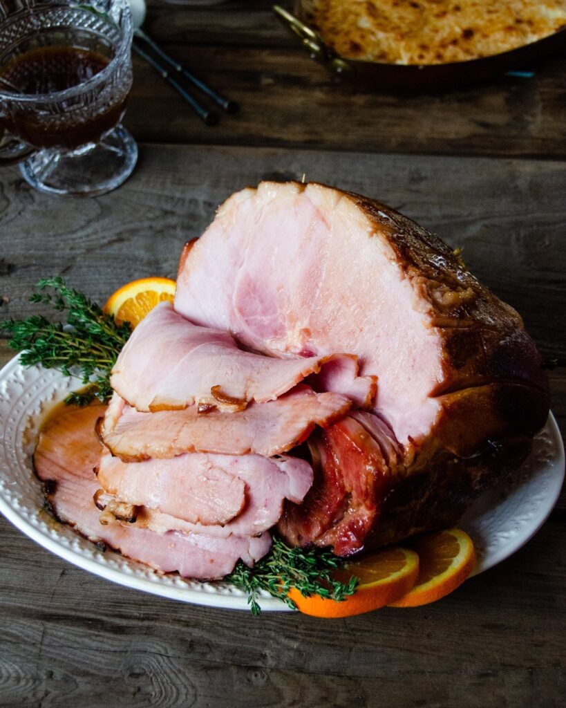 Baked Ham with Madeira and Orange on platter with slices cut.