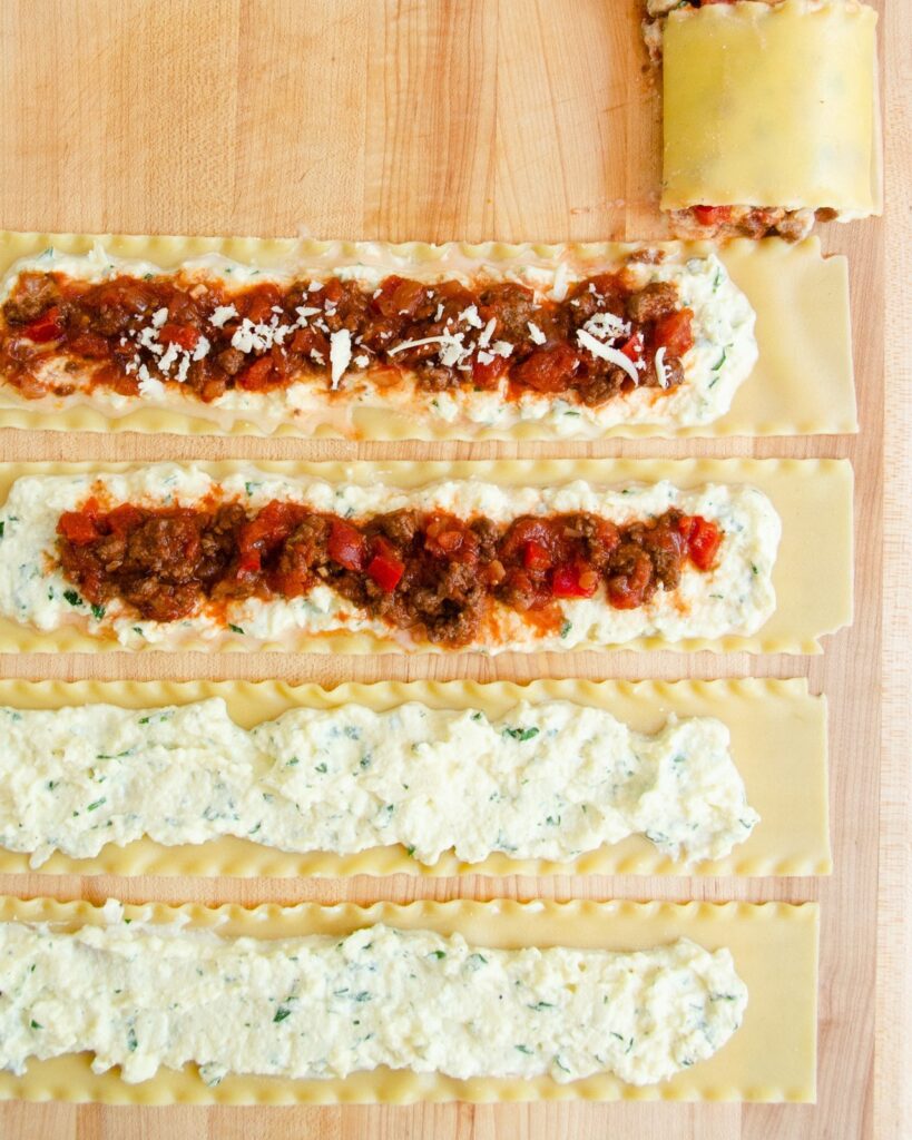 Lasagna Roll Ups being assembled on a wooden board.
