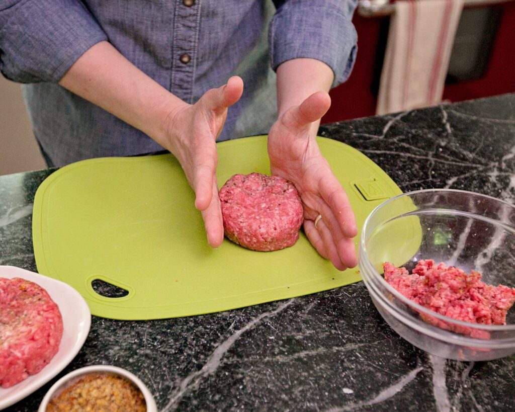 Shaping a burger into a perfectly round patty.
