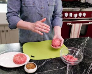 Throwing burger meat from hand to hand to form a ball.