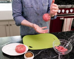 Throwing burger meat from hand to hand to form a ball.