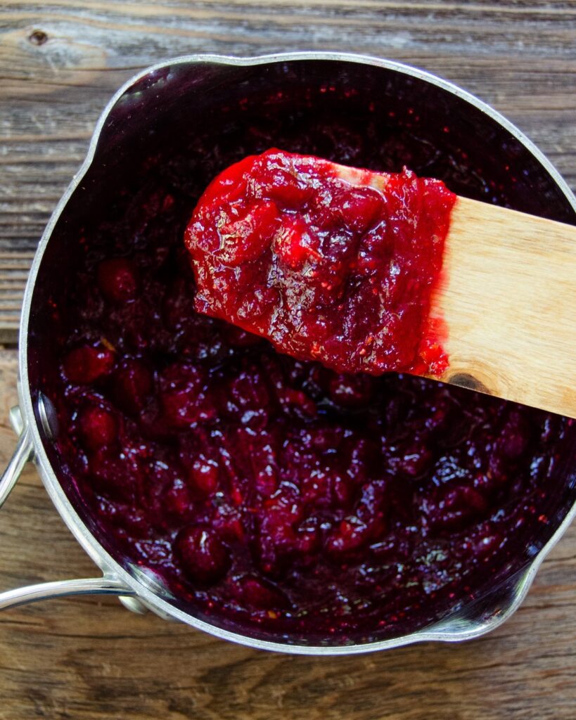 Cranberry Sauce in a saucepan, coating a wooden spoon.