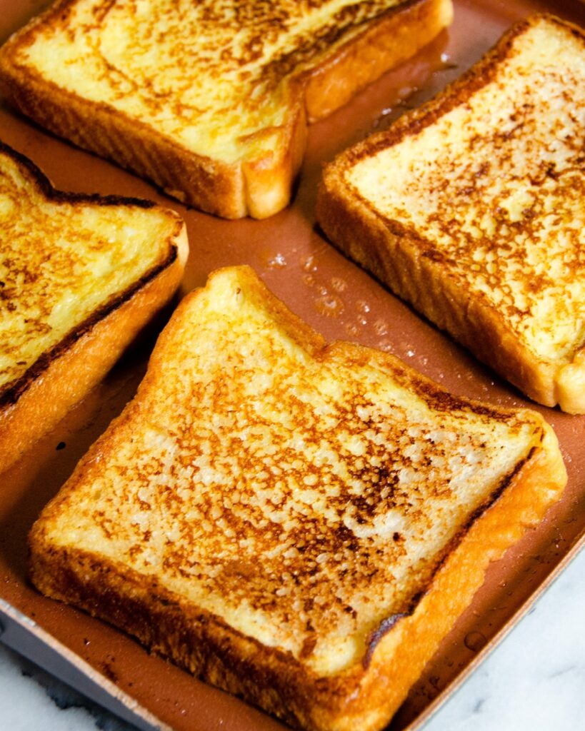 French Toast cooking on a square griddle.