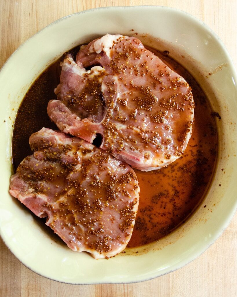Honey Mustard Pork Chops in marinade in a shallow dish.