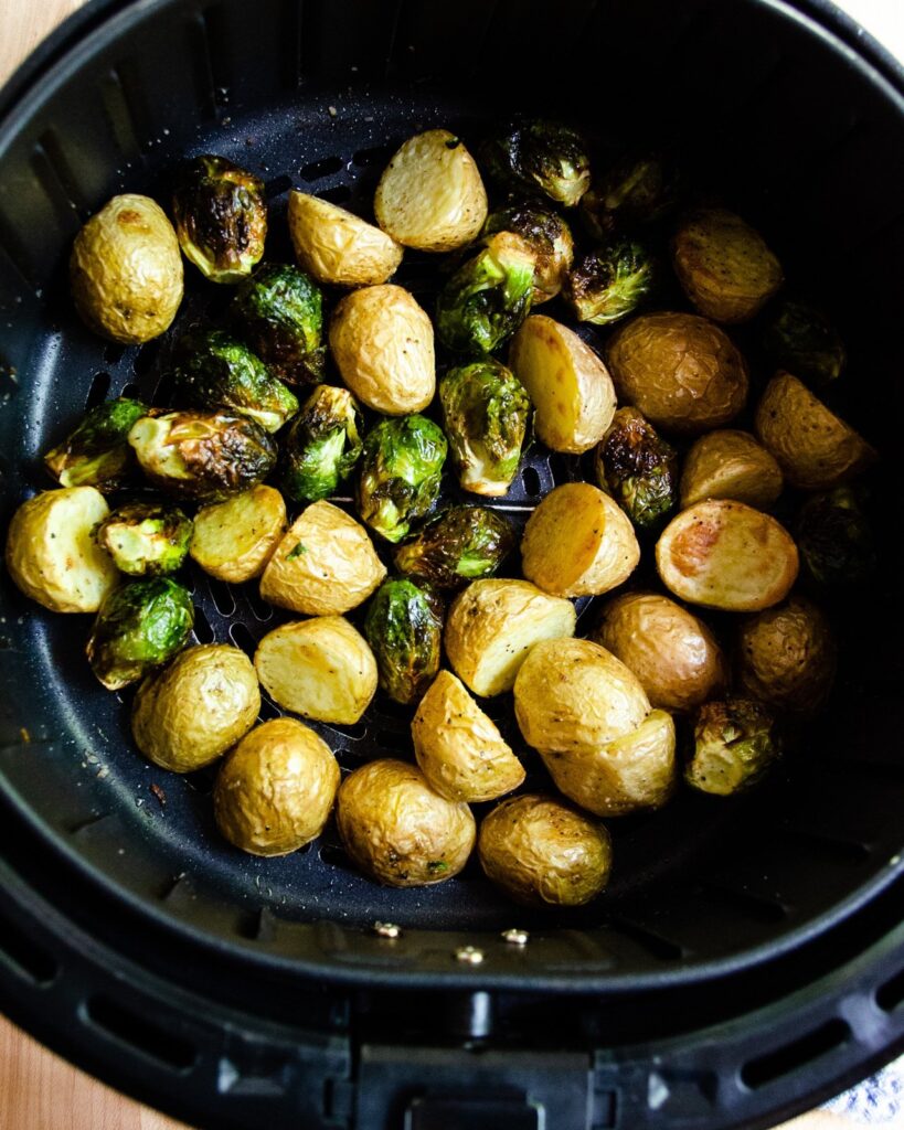 Brussels Sprouts and baby gold potatoes in an air fryer basket.