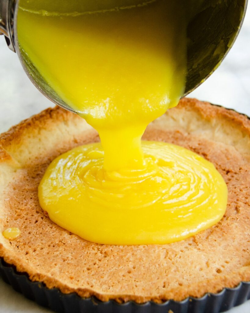 Pouring lemon curd into a crust for lemon meringue tart.