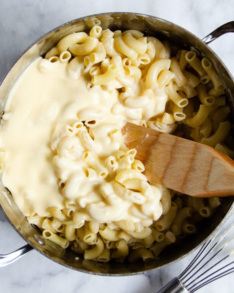Macaroni and Cheese sauce being stirred together in a stock pot.