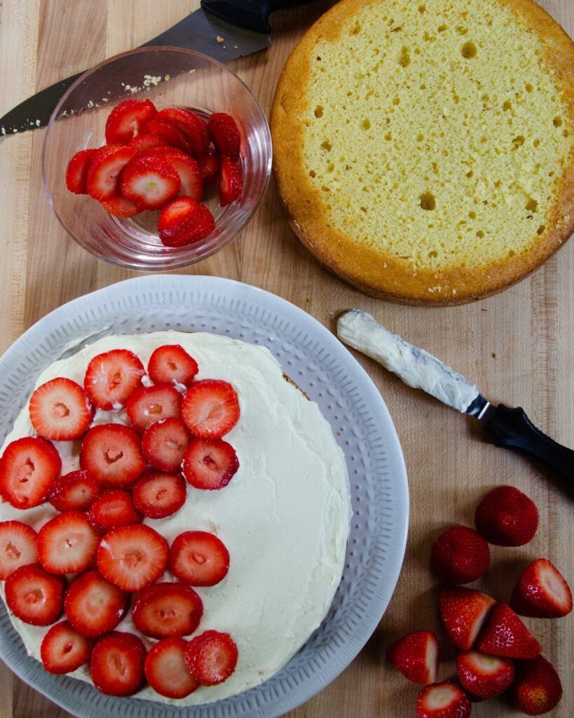 Strawberry Lemon Mascarpone Shortcake being assembled on a wooden board.