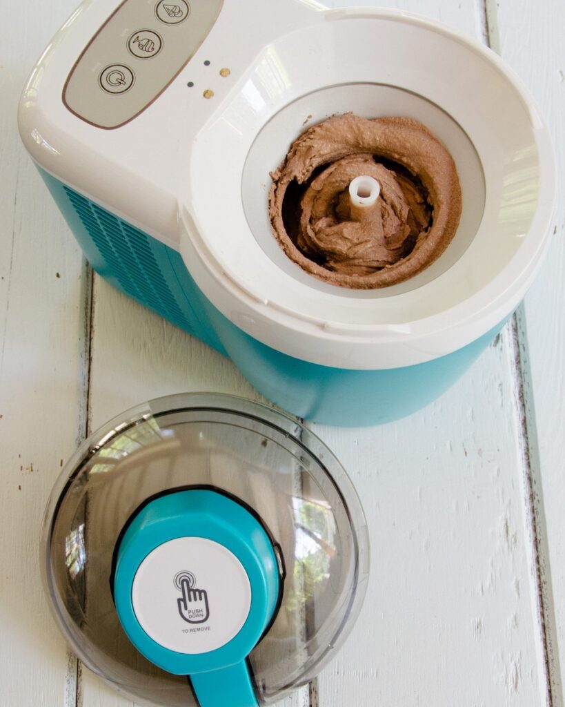 Sugar Free Chocolate ice Cream in an ice cream maker on a white wooden table.