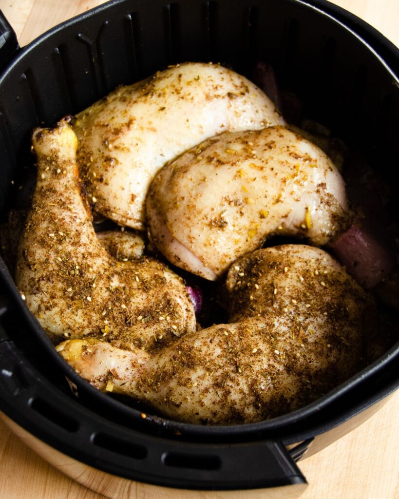 Marinated za'atar chicken legs in an air fryer basket.