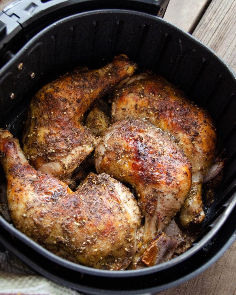 Cooked za'atar chicken legs in an air fryer basket.