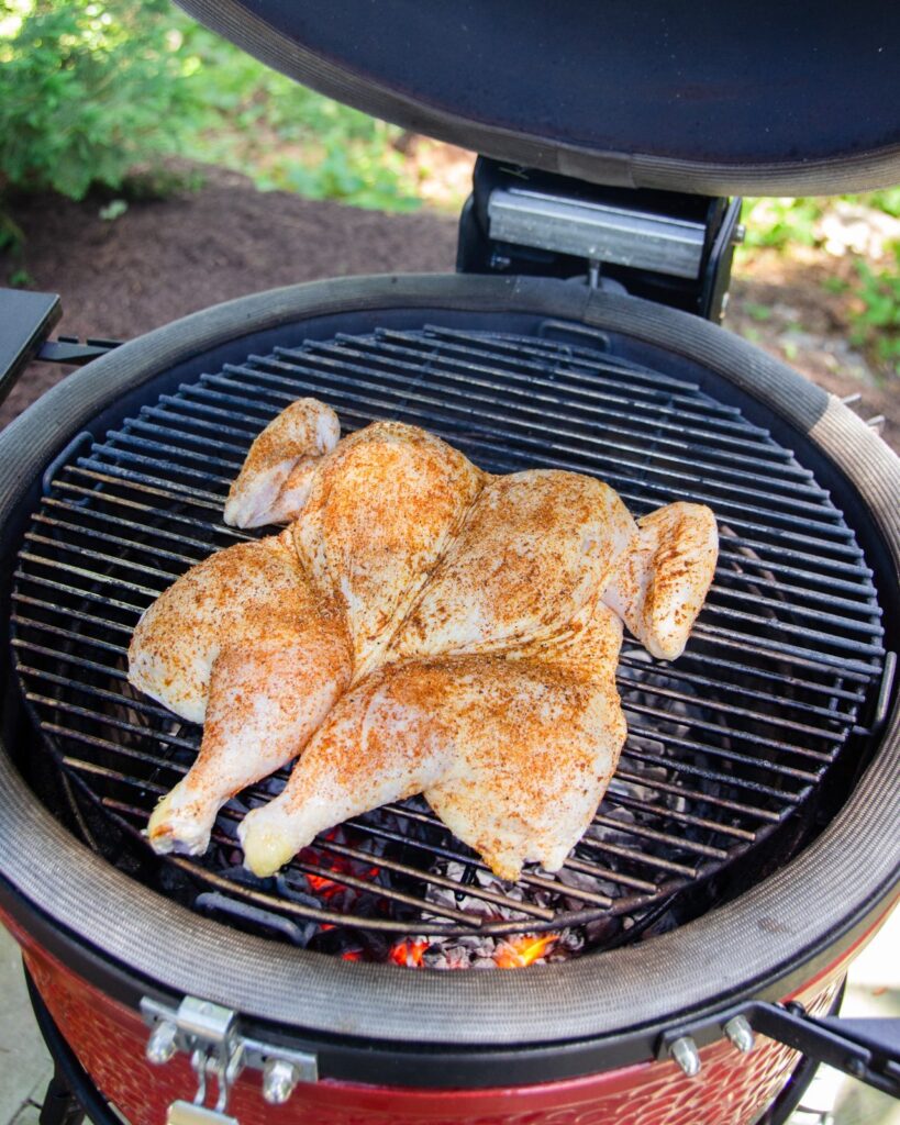 Spice rubbed spatchcocked chicken on a grill.