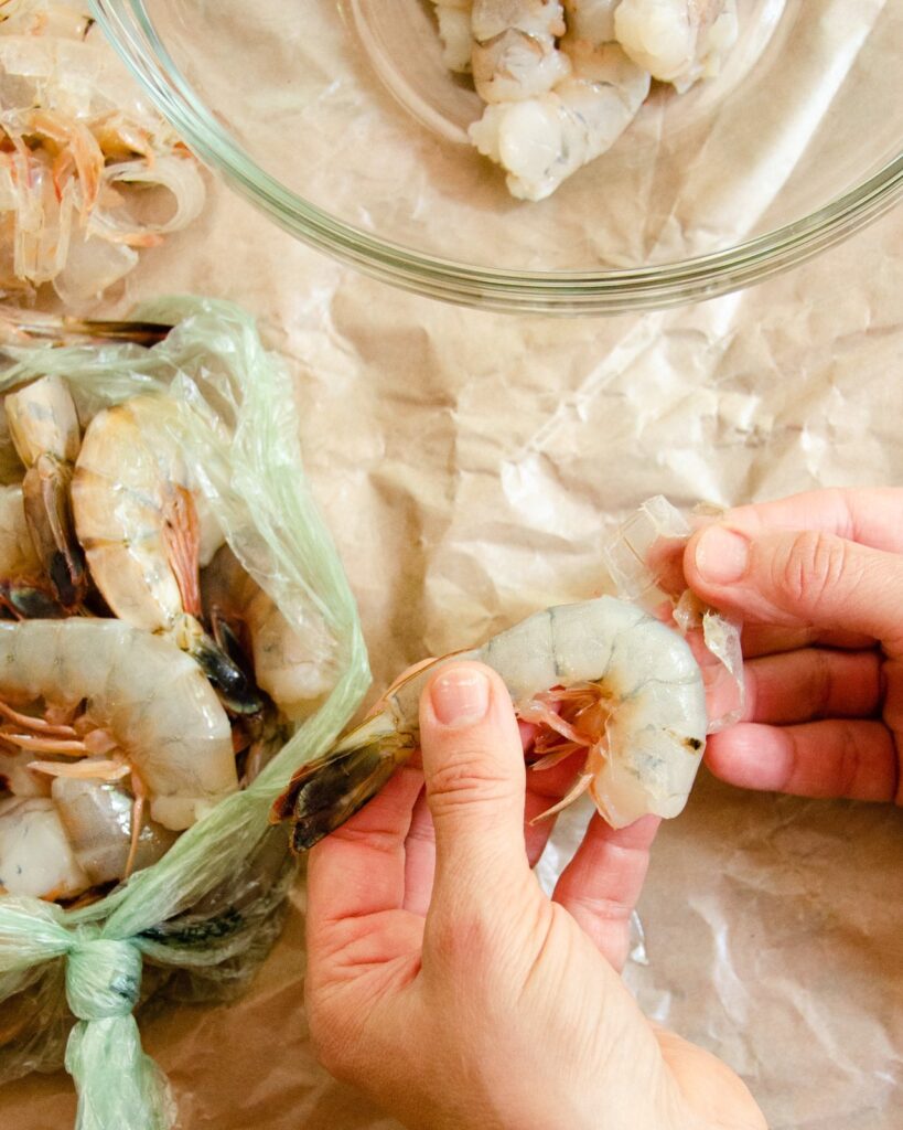 Hands peeling shrimp.