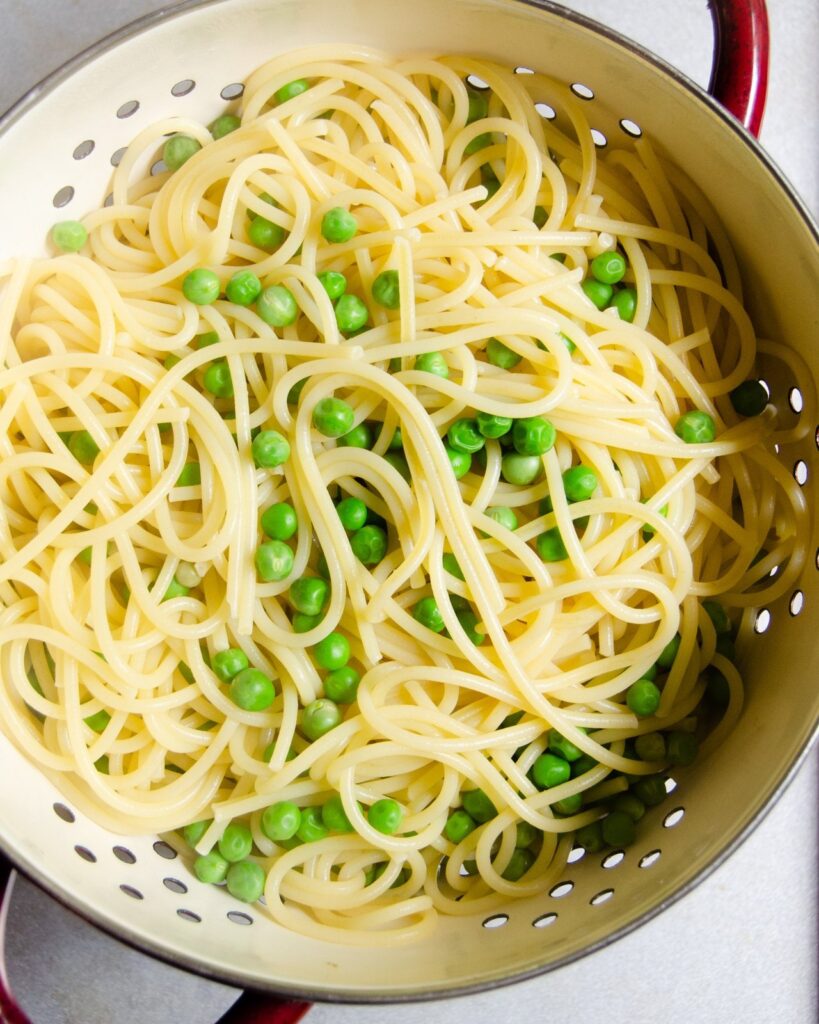 Spaghetti and Peas in a colander.