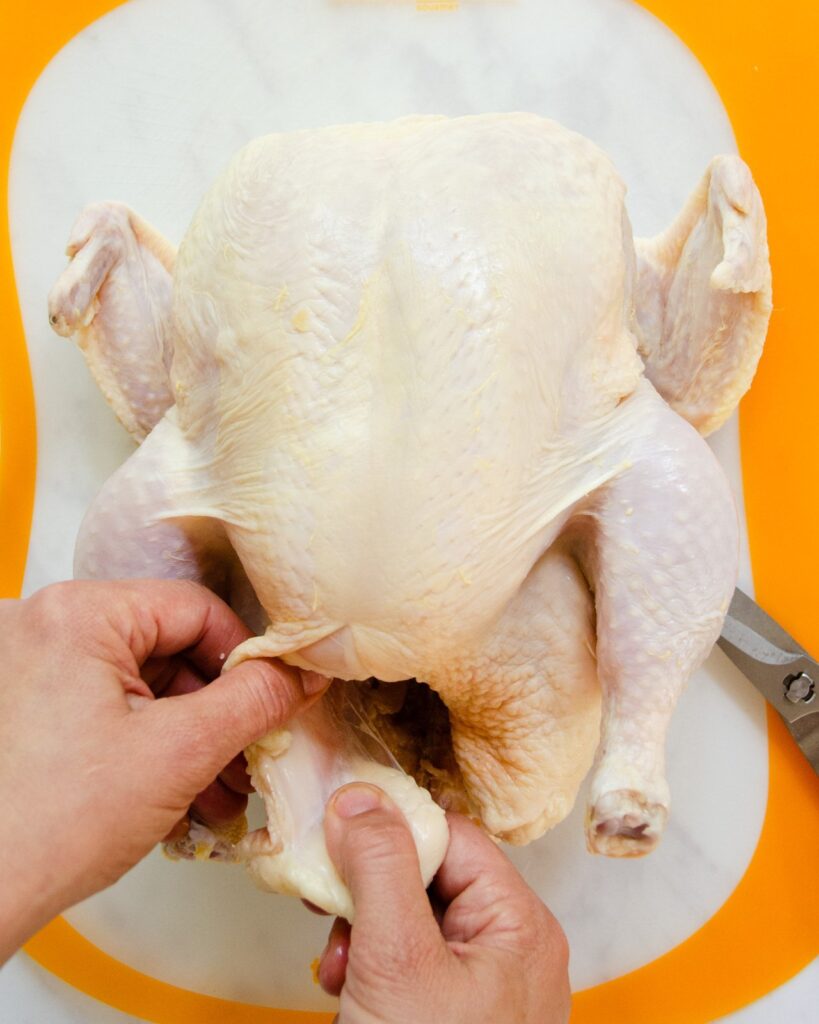 Removing the extra fat from inside a chicken.