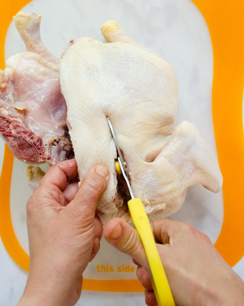 Cutting down the second side of the backbone of chicken.