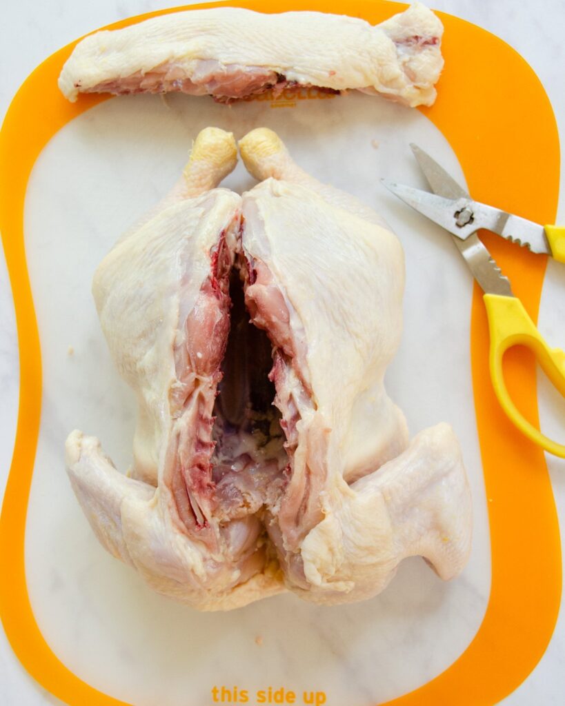 A chicken on a cutting board with backbone removed.