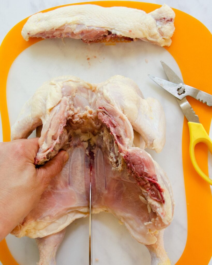 Scoring the underside of the breast bone of a chicken.