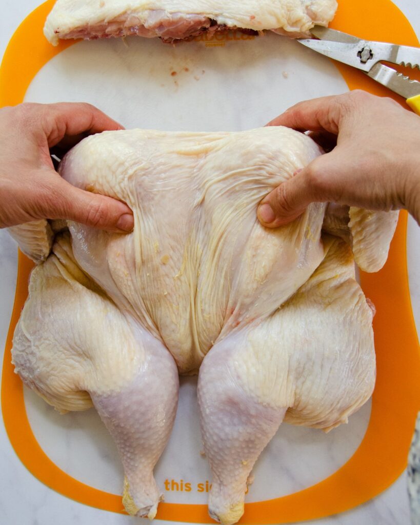 A spatchcocked chicken on a cutting board.
