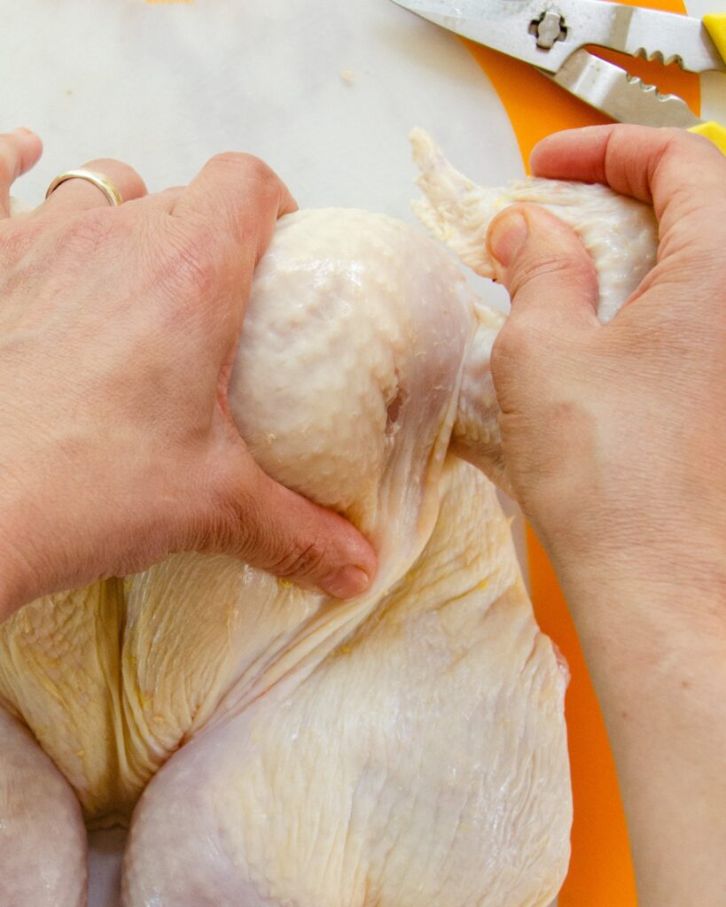 Tucking a chicken wing behind the breast - the last step in how to spatchcock a chicken.
