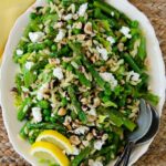 Spring green salad on a white oval platter with serving spoons.