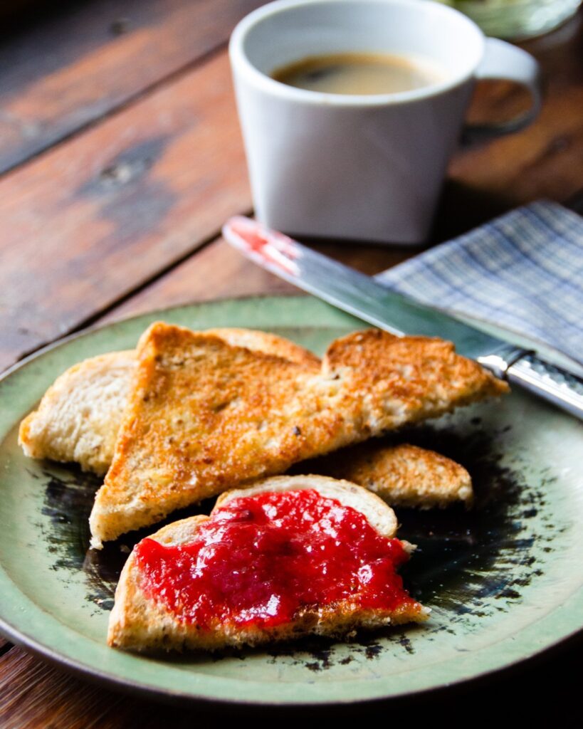 Strawberry Rhubarb Jam on toast on a green plate with a cup of coffee.