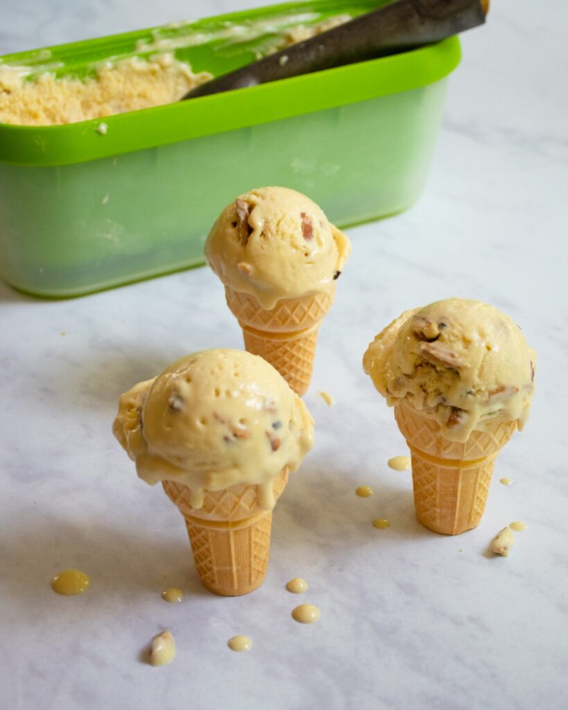 Three cones of brown butter ice cream  on a marble counter.