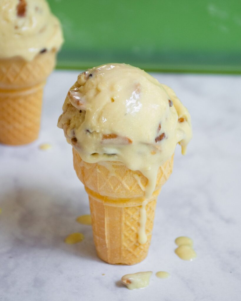 One single ice cream cone with ice cream dripping down the side..