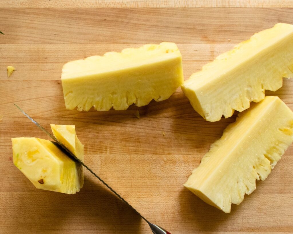 Four quarters of pineapple with the stem being removed from one of them.