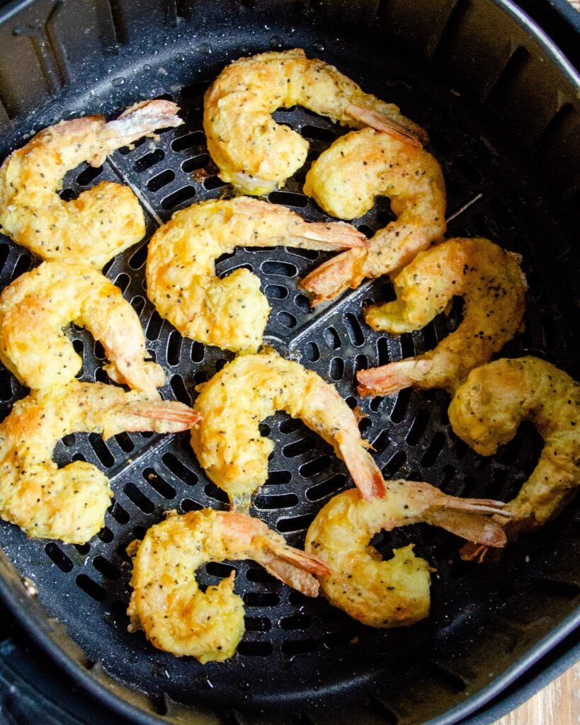 Salt and pepper shrimp in an air fryer basket.