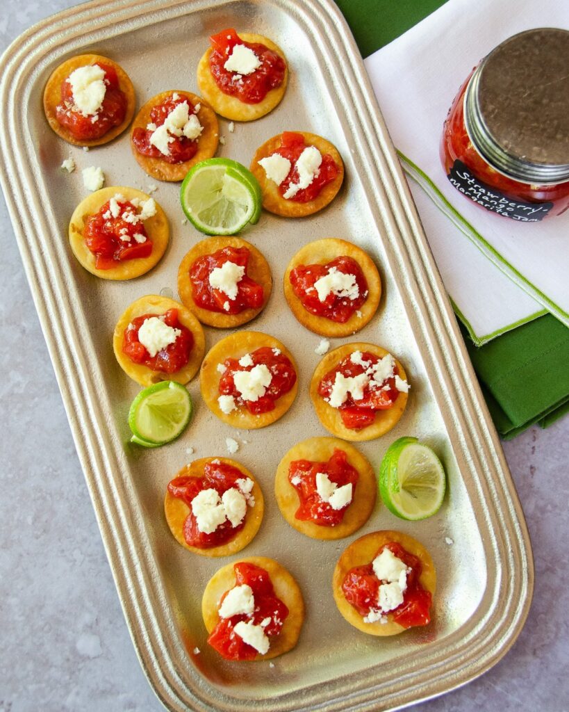 Tortilla crostini with strawberry mango margarita jam and queso fresco on a silver tray.