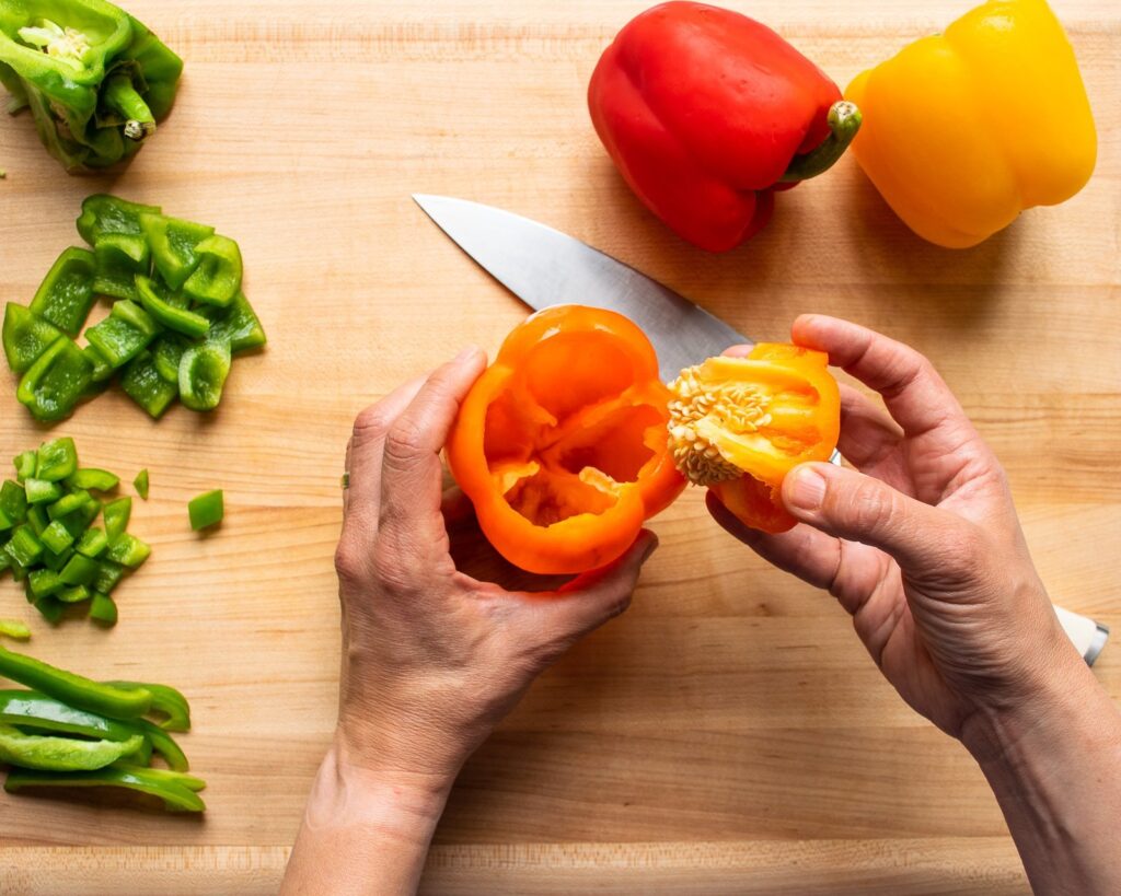Removing the core from an orange pepper.