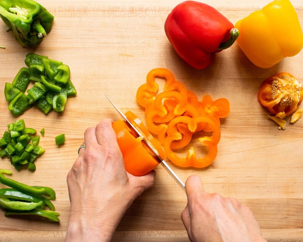 Hands showing how to cut a bell pepper into rings.