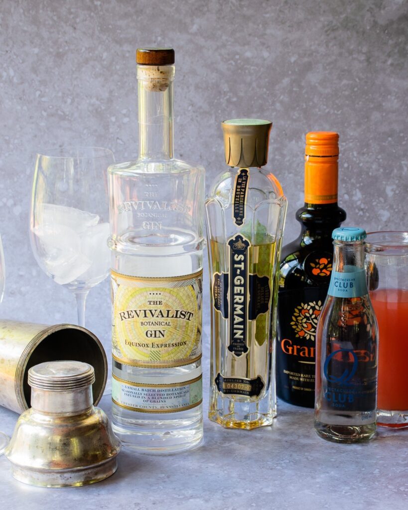 All the ingredients for a pamplemousse fizz with a cocktail shaker near by.