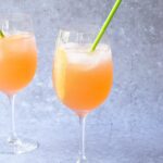 two wine glasses with pamplemousse fizz inside, along with a green straw.