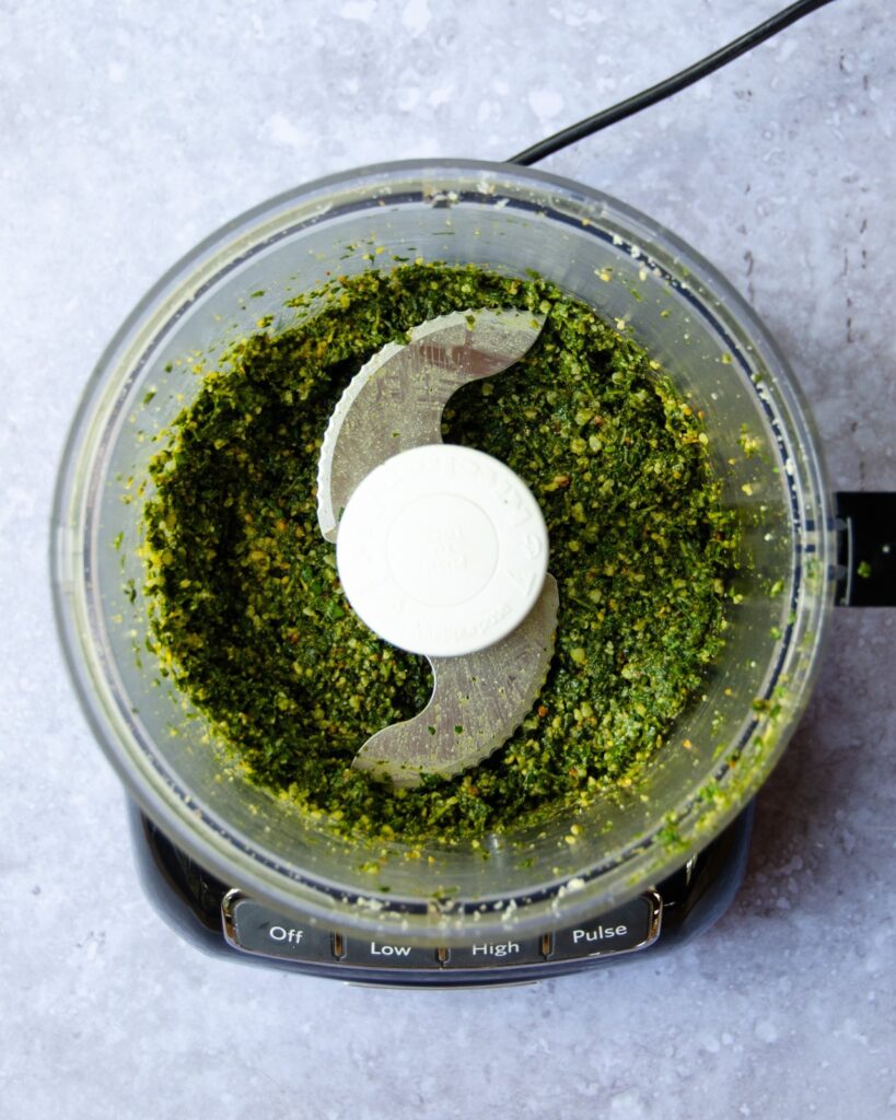 Pesto in a food processor after the olive oil has been added - a darker shade of green.