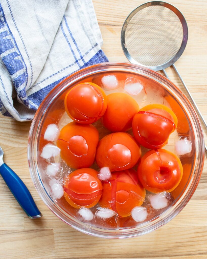 Tomatoes in an ice bath, being shocked - a step in how to make tomato concassé.