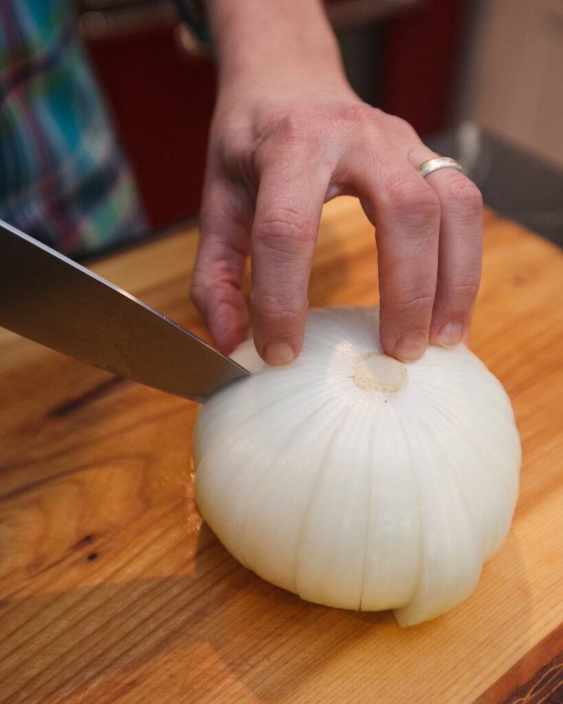 A knife cutting an onion into petals to make a blooming onion.