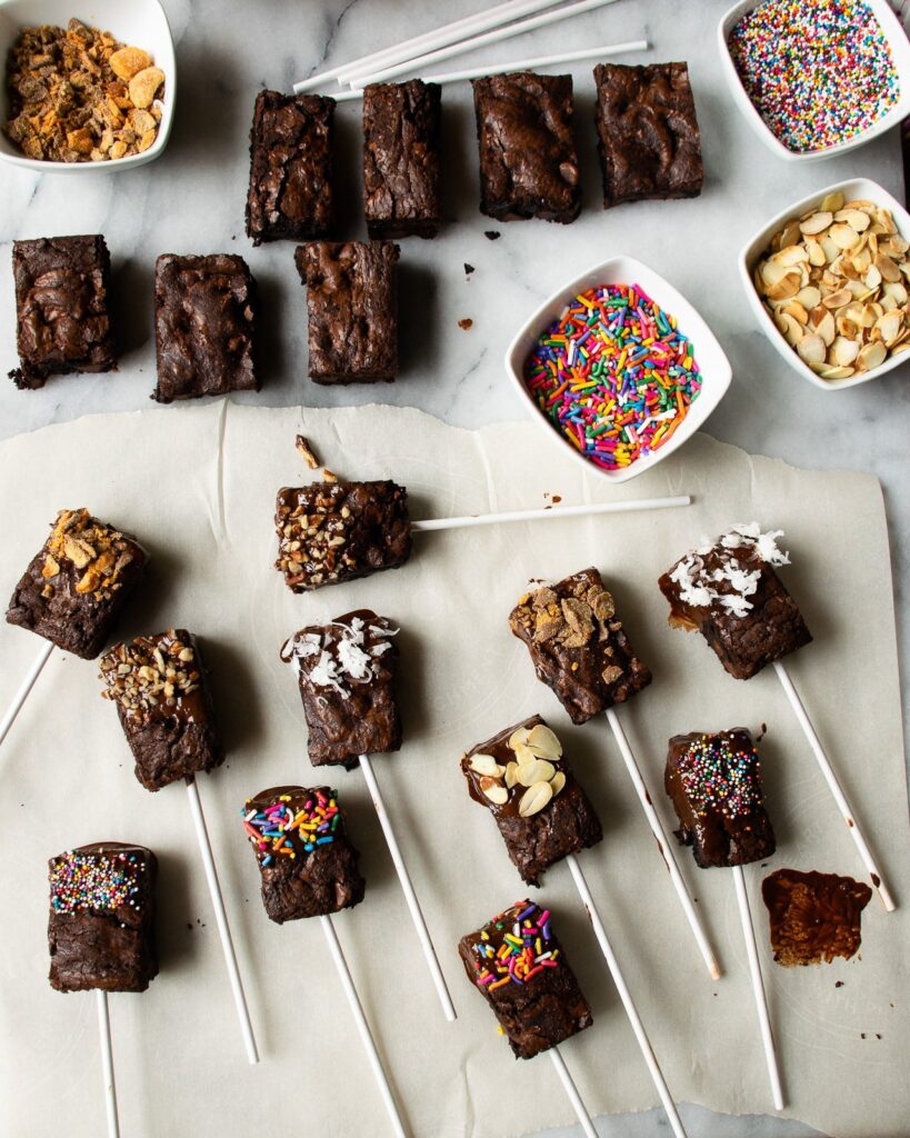Brownie pops being decorated with various toppings.