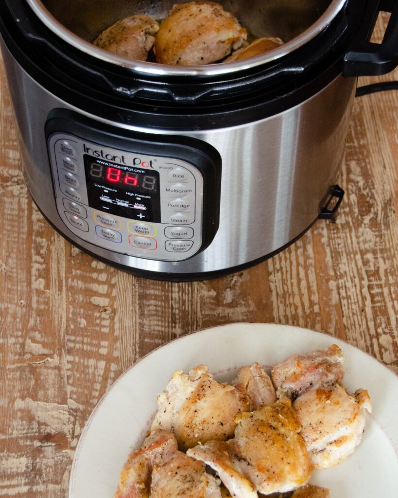 Browned chicken  on a plate in front of an Instant Pot® .