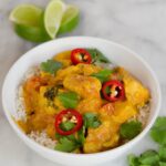 Chicken with Red Curry and Coconut in a white bowl on a marble counter.