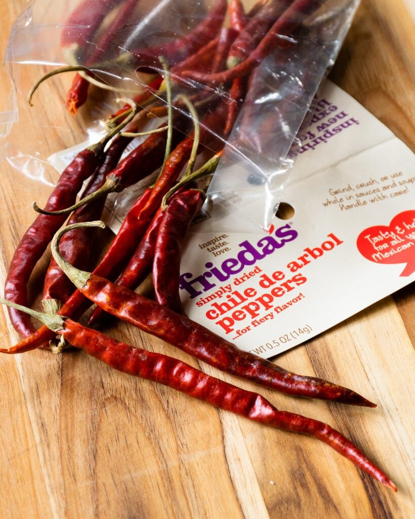Dried red chili peppers on a cutting board with a label.