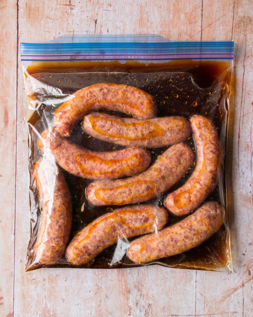 bratwurst in a zipper sealable plastic bag with beer marinade on a table.