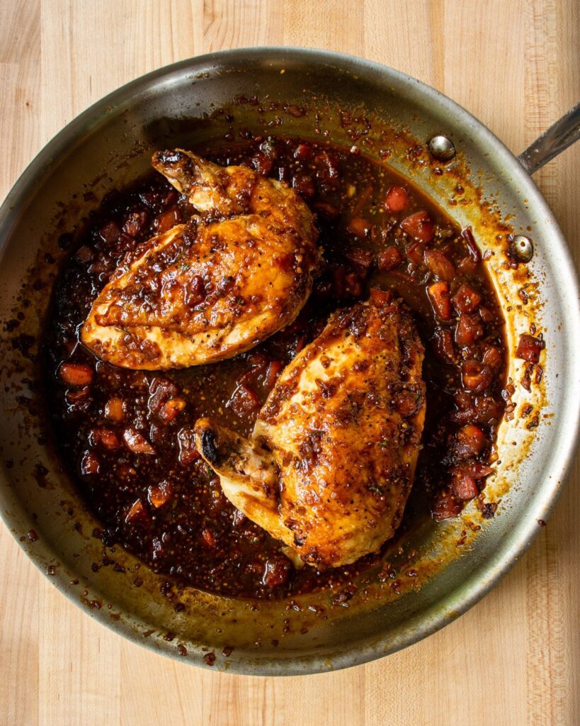 Two chicken breasts in a skillet with balsamic pan sauce.