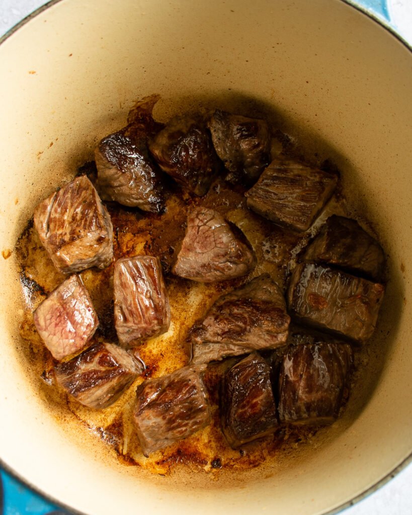 Beef stew meat browning in a cast iron Dutch oven.